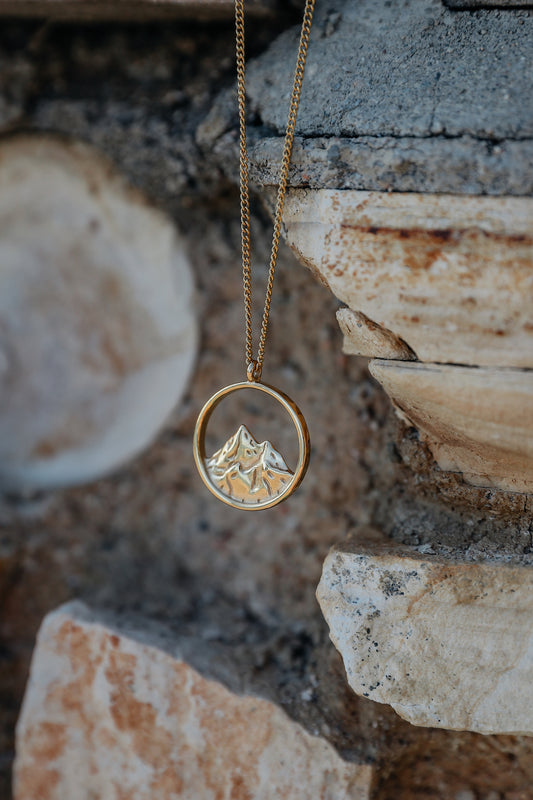 Breaking point necklace hanging from a stone backdrop
