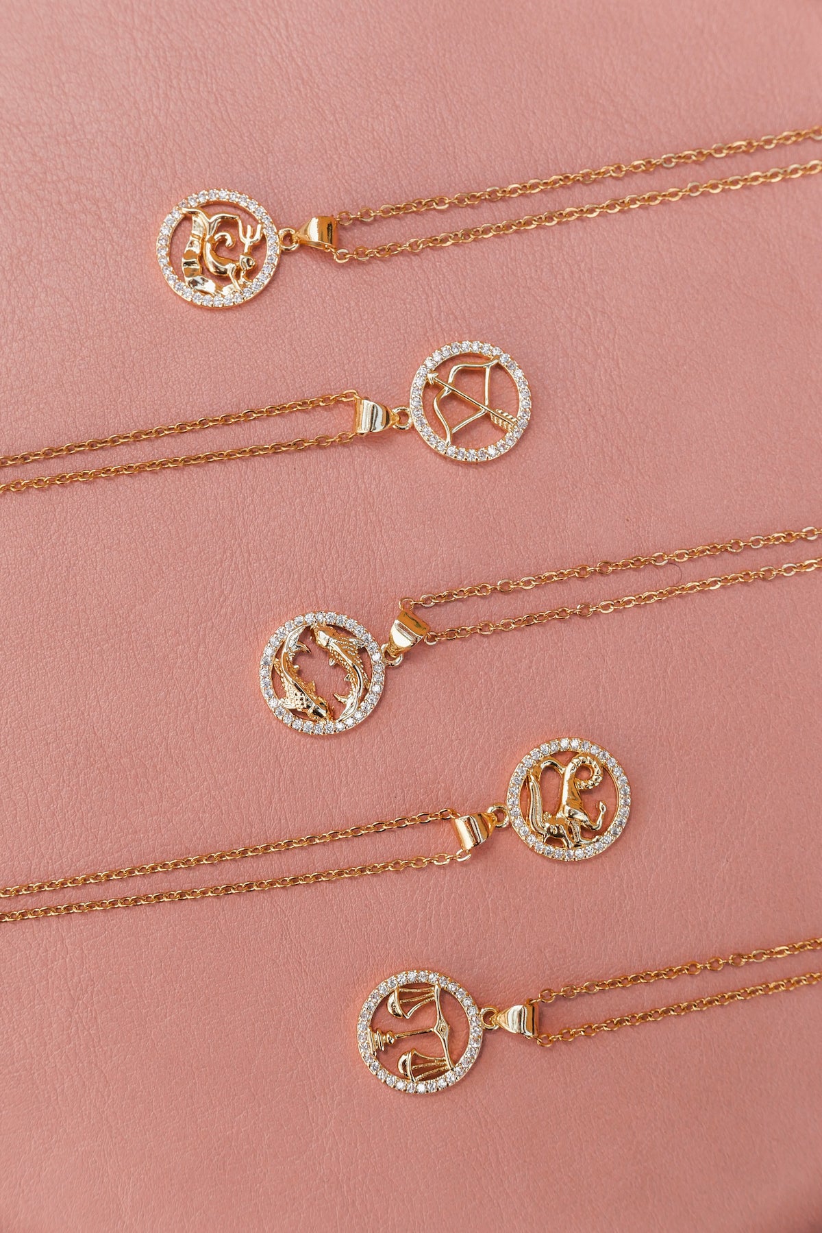 6 styles of zodiac necklace laying flat on pick backdrop