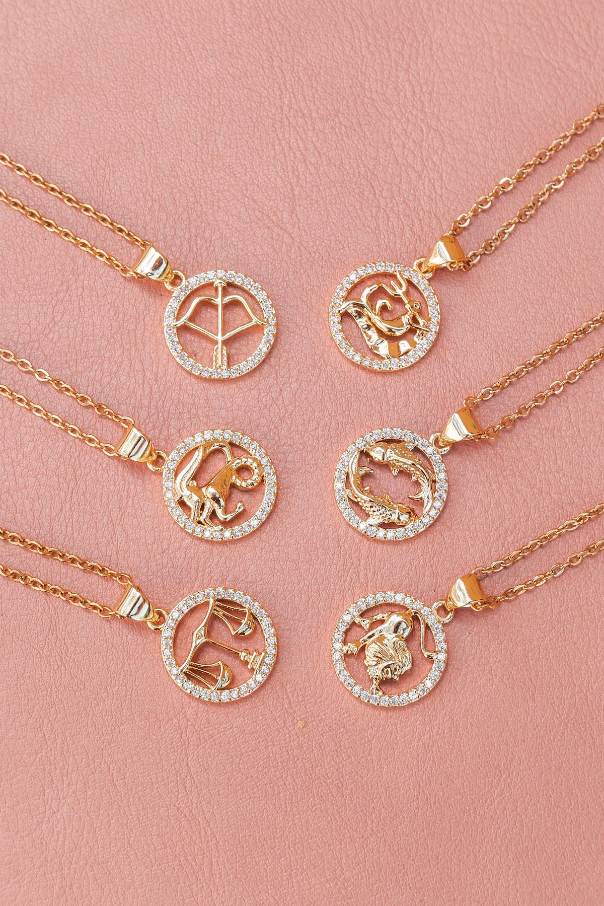 6 styles of zodiac necklace laying flat on pick backdrop