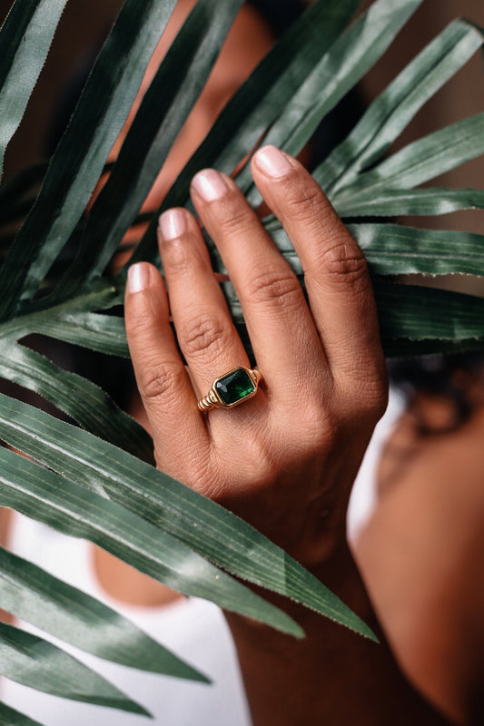 Emerald statement ring  on model hand holding a plant