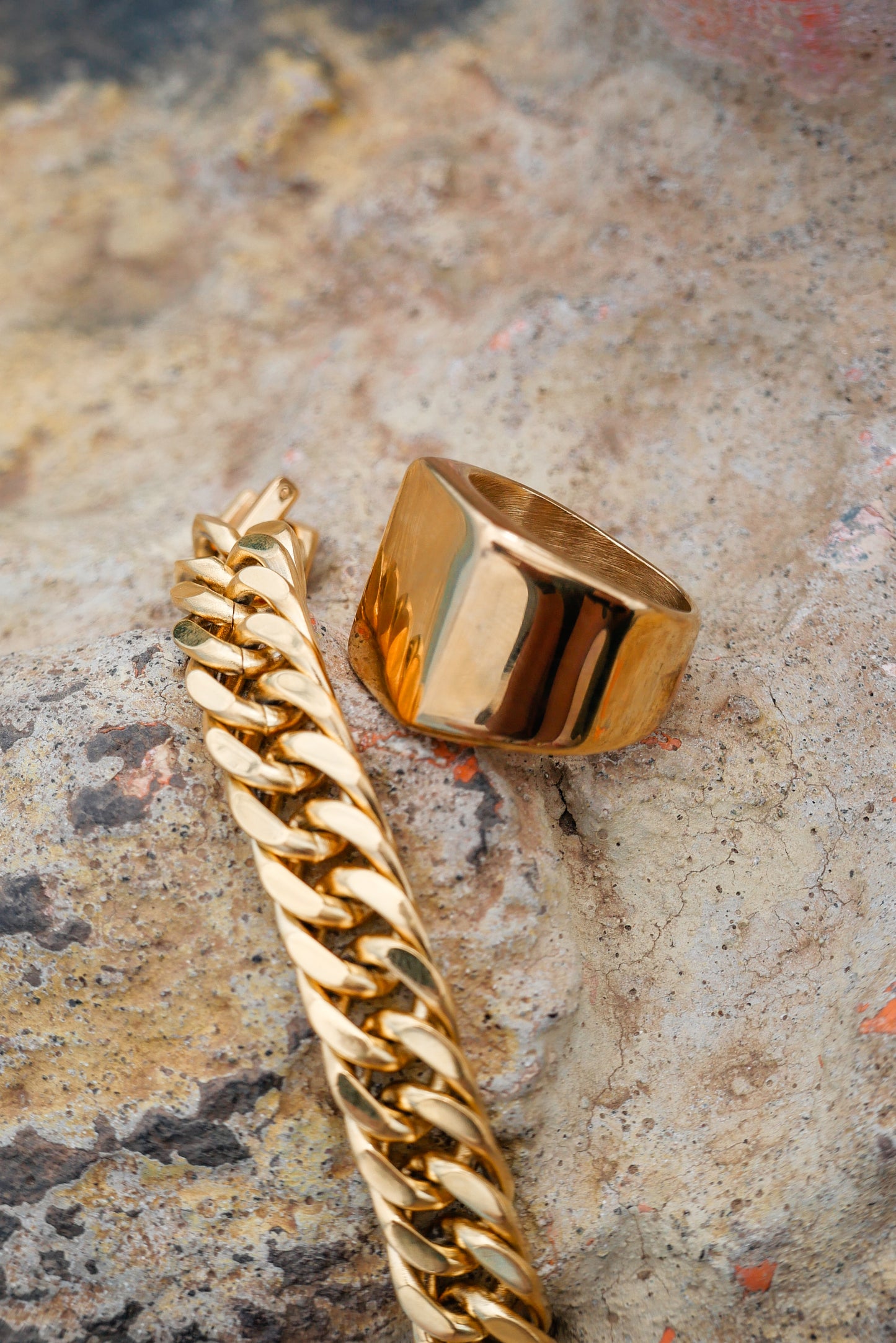 Gold amor bold mens ring and gold lets links bracelet on nature backdrop