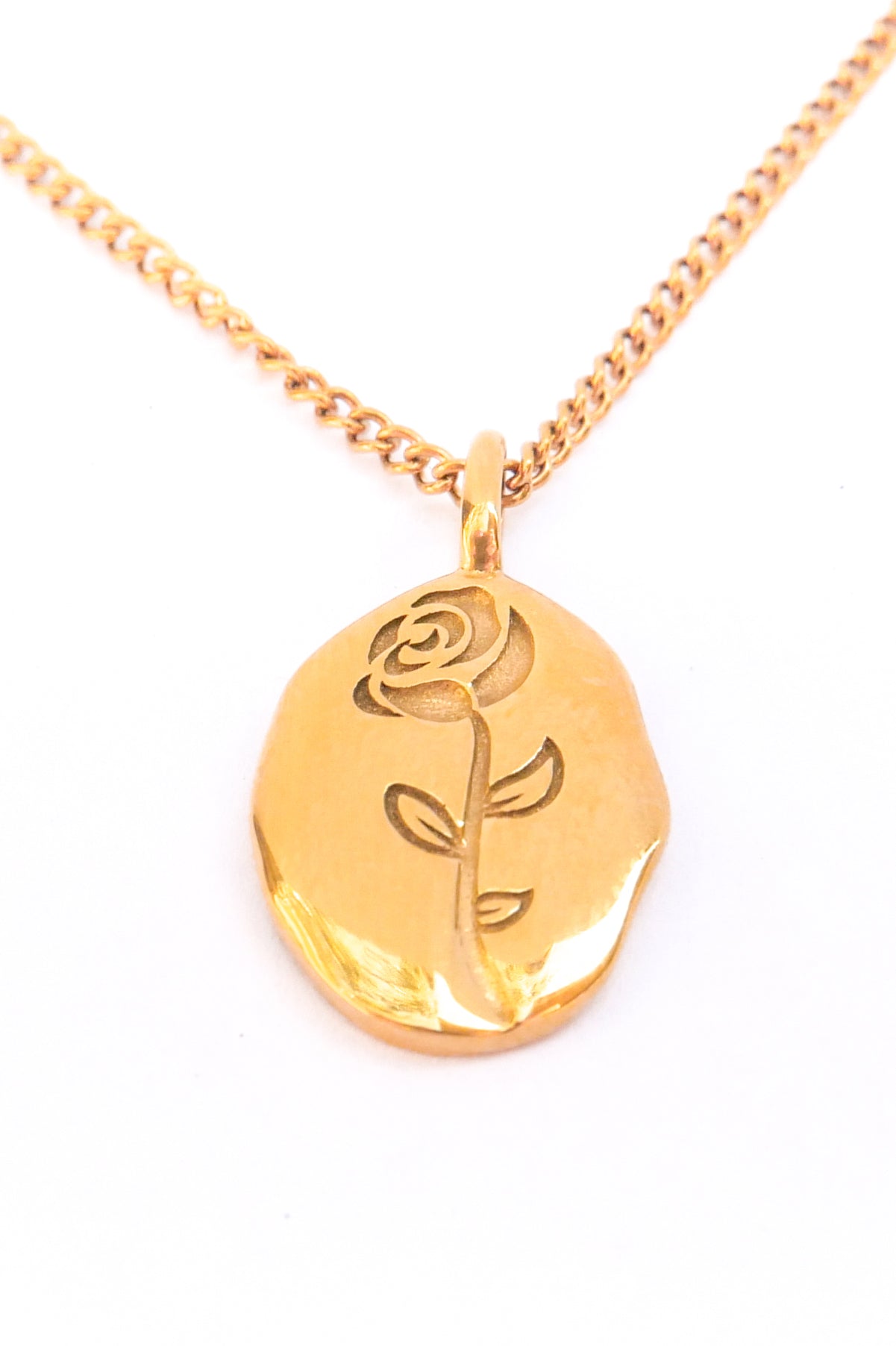 Close up view of embossed rosa necklace against a white backdrop